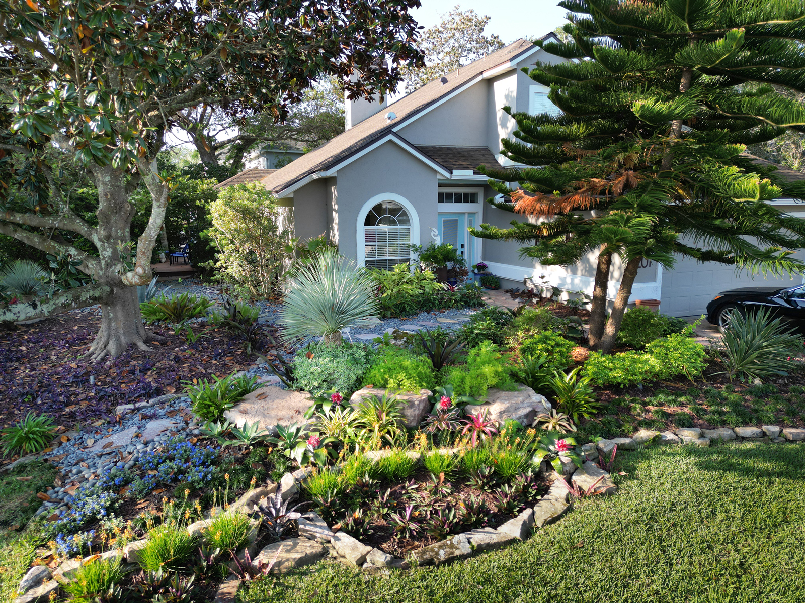 A meticulously arranged rock border separating flower beds from the lawn, adding a rustic touch to the garden