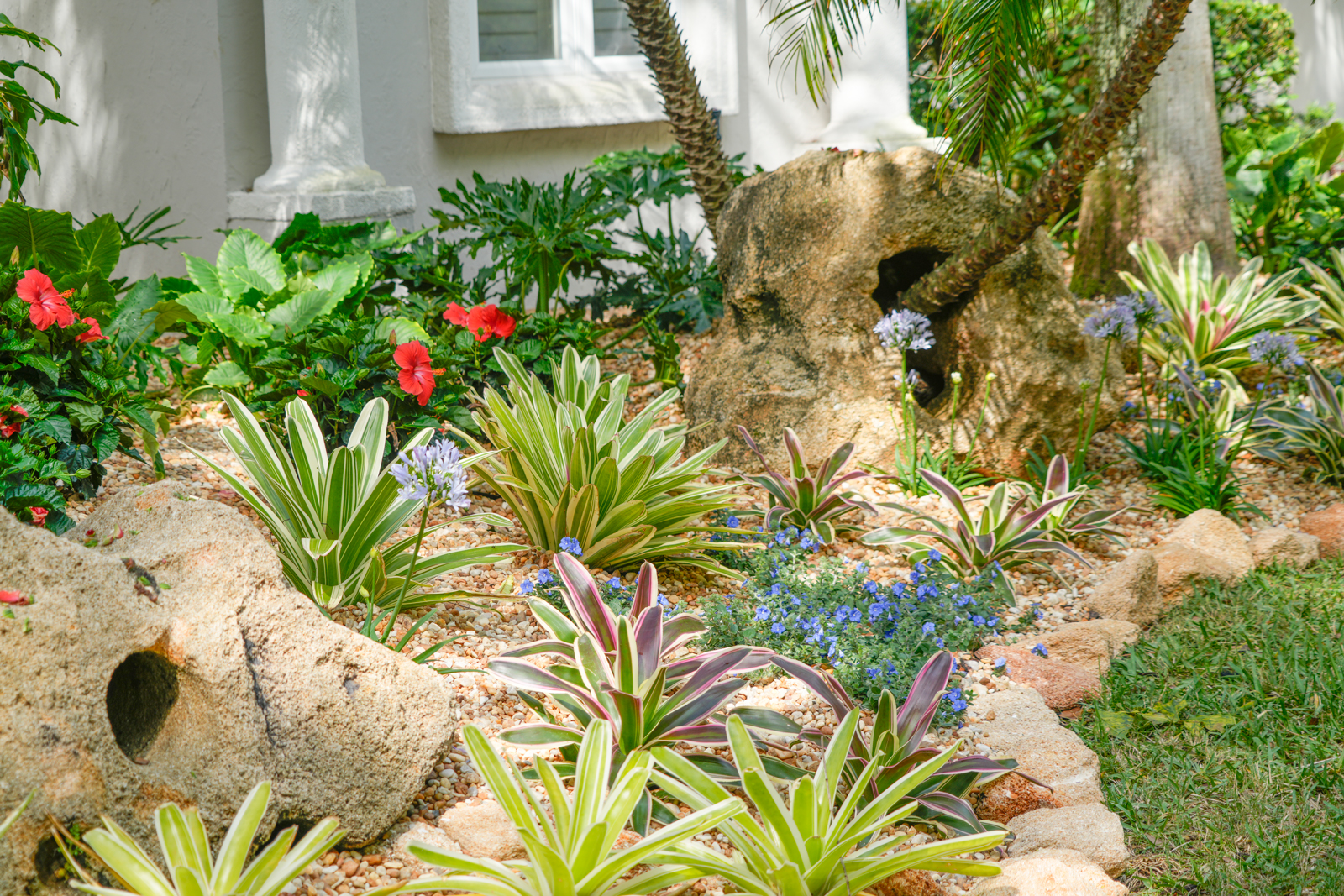 A variety of stone features including waterfalls, statues, and stepping stones, skillfully integrated into the landscape for visual and textural contrast