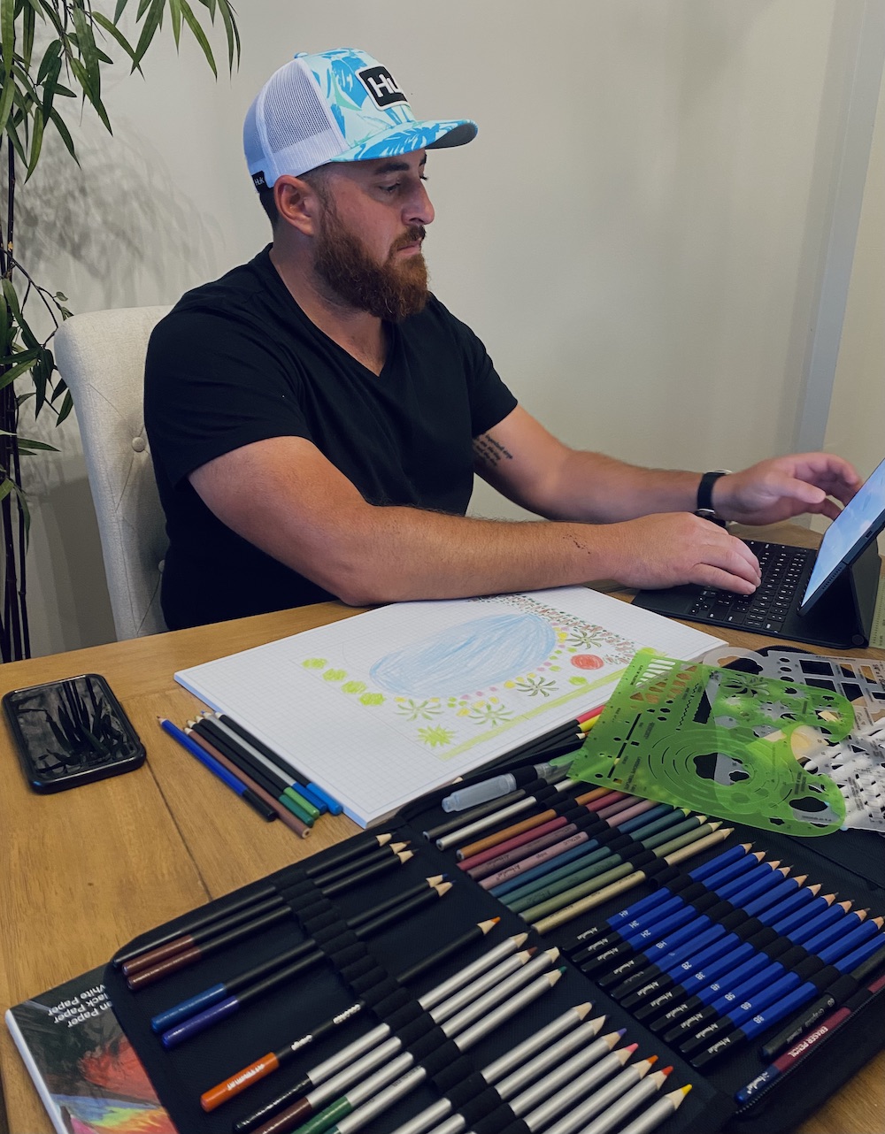 Chris intently working on a computer, digitally rendering a landscape design with intricate details, showing a mix of plants, hardscapes, and layout features