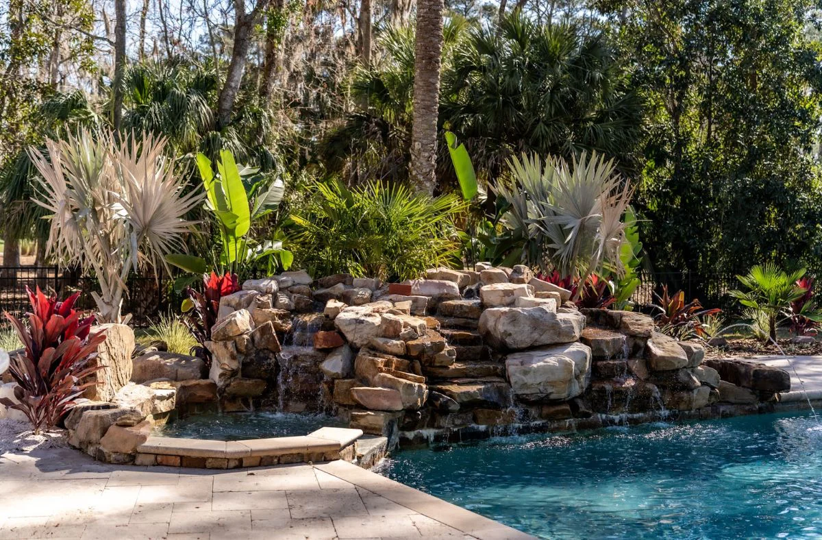 luxury outdoor living space features including natural stone waterfalls to enhance backyard entertainment spaces